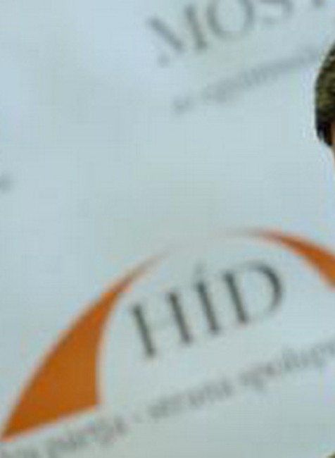 bela bugar, zamysleny, za nim logo Most-Híd