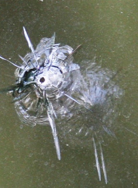 detail následkov streľby projektilu na rozbitom okne