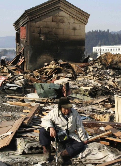 Zúfalý starček sedí na ruinách zničeného mestečka v Japonsku