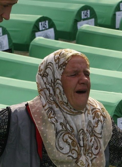 Príbuzní upokojujú  Bosniansku Moslimku, ktorá plače nad hrobmi obetí genocídy v Srebrenici.