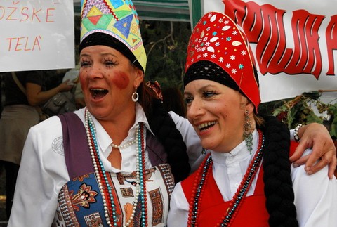 dve zeny prezlecene za carodejnice spievaju, za nimi napis bozske tela