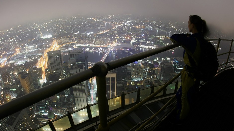 Veľkomesto z výšky, nočné svetlá, žena sa pozerá