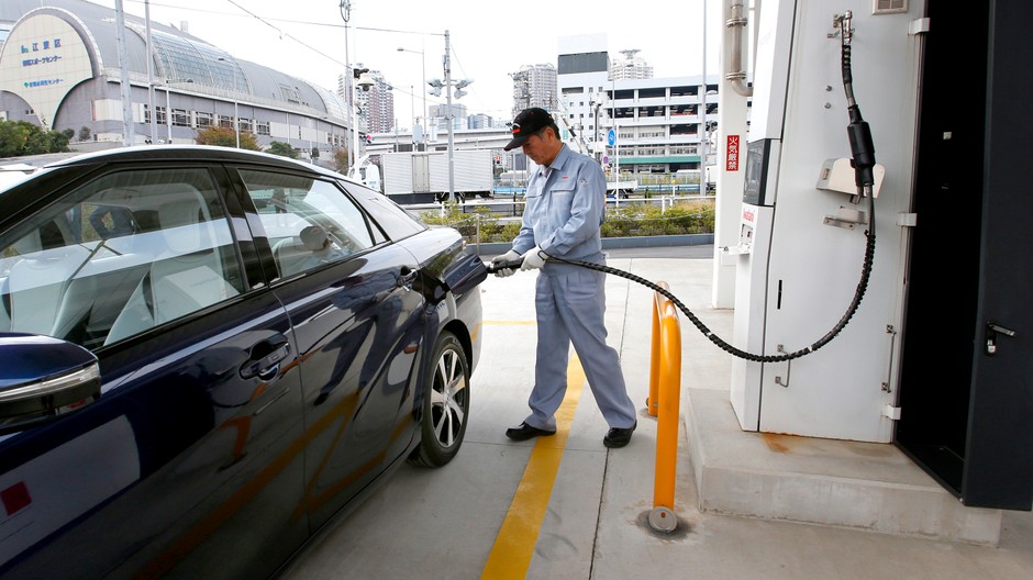 Pracovník čerpacej stanice tankuje do auta vodík