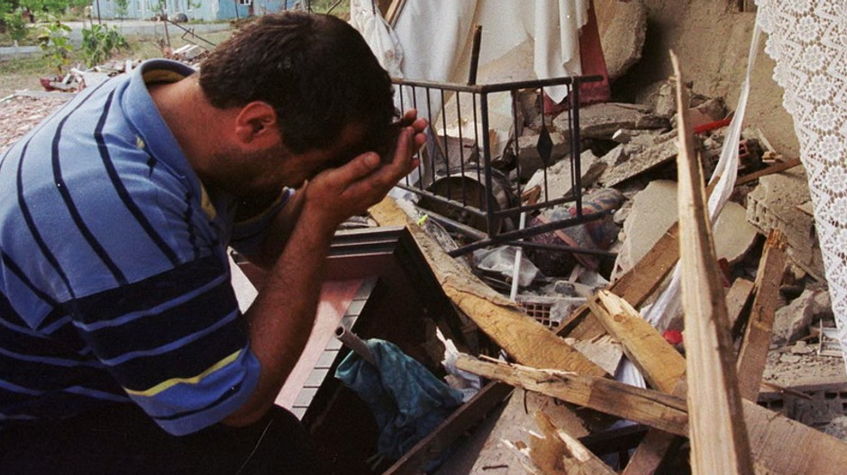 zronený muž sedí v troskách domu po zemetrasení