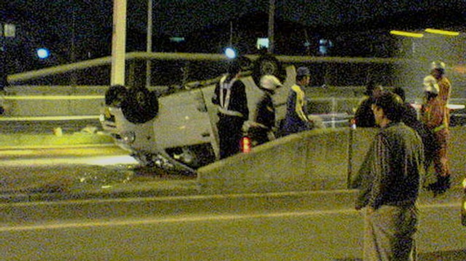 Osobné auto na streche, betónový múrik, tma, noc, ľudia, hasiči